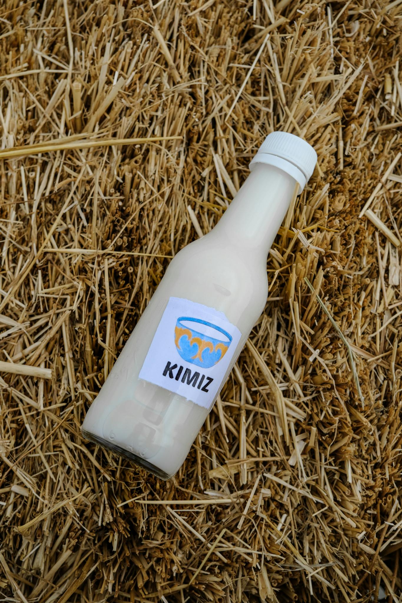 A bottle of kumis positioned on a straw bale, highlighting traditional fermentation.