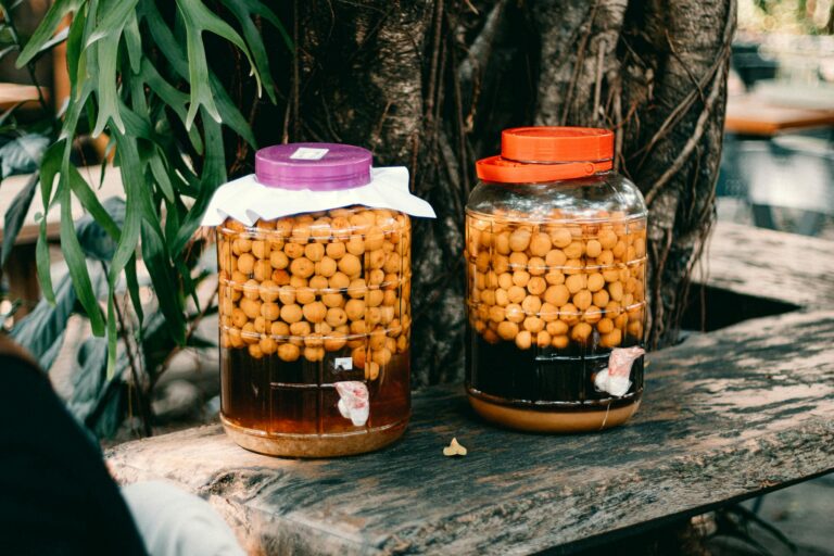 Two jars filled with preserved fruits resting on a rustic outdoor wooden table.